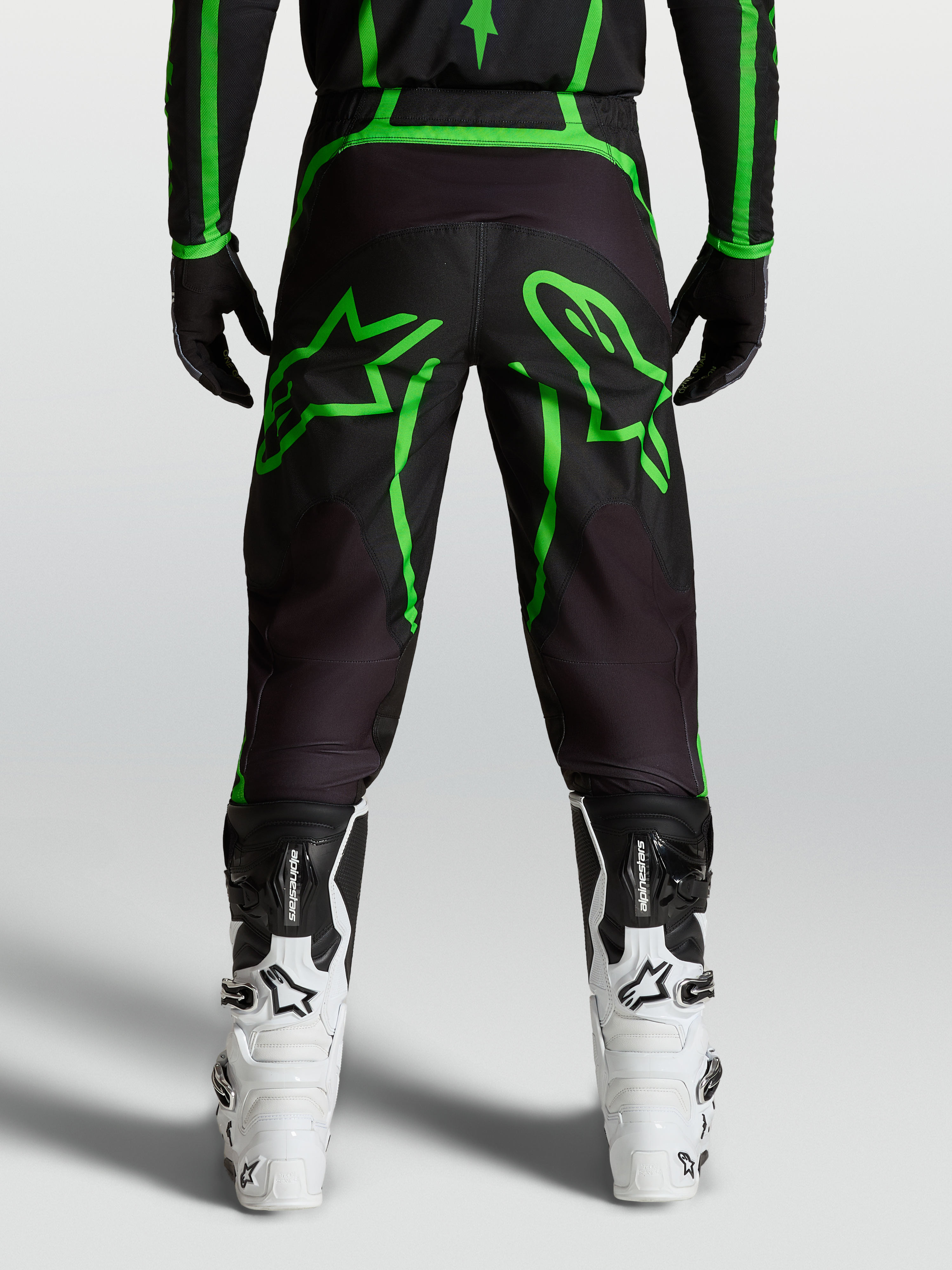 Alpinestars Fluid Apex V2 byxor, svarta och gröna motocrossbyxor för herr med stor stjärngrafik, vy bakifrån på modell.