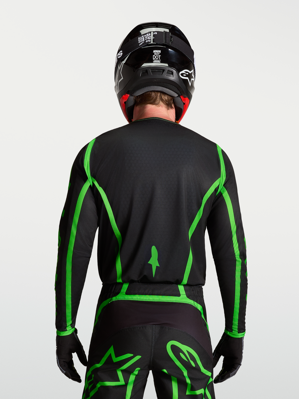 Alpinestars Fluid Apex V2 tröja för motocross, svart och neongrön, bakifrån på modell som visar förlängt ryggslut.