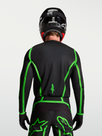 Alpinestars Fluid Apex V2 tröja för motocross, svart och neongrön, bakifrån på modell som visar förlängt ryggslut.