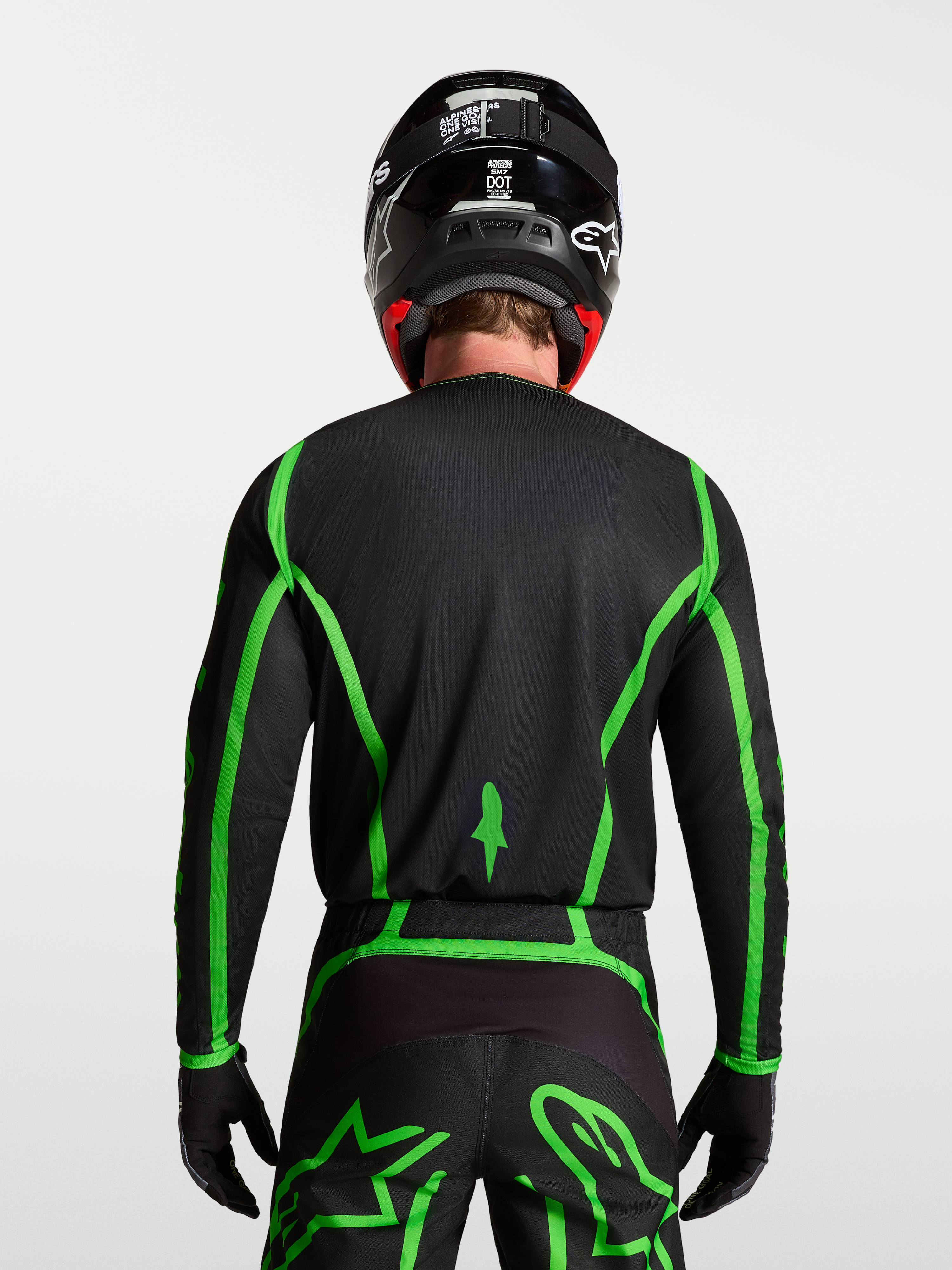 Alpinestars Fluid Apex V2 tröja för motocross, svart och neongrön, bakifrån på modell som visar förlängt ryggslut.