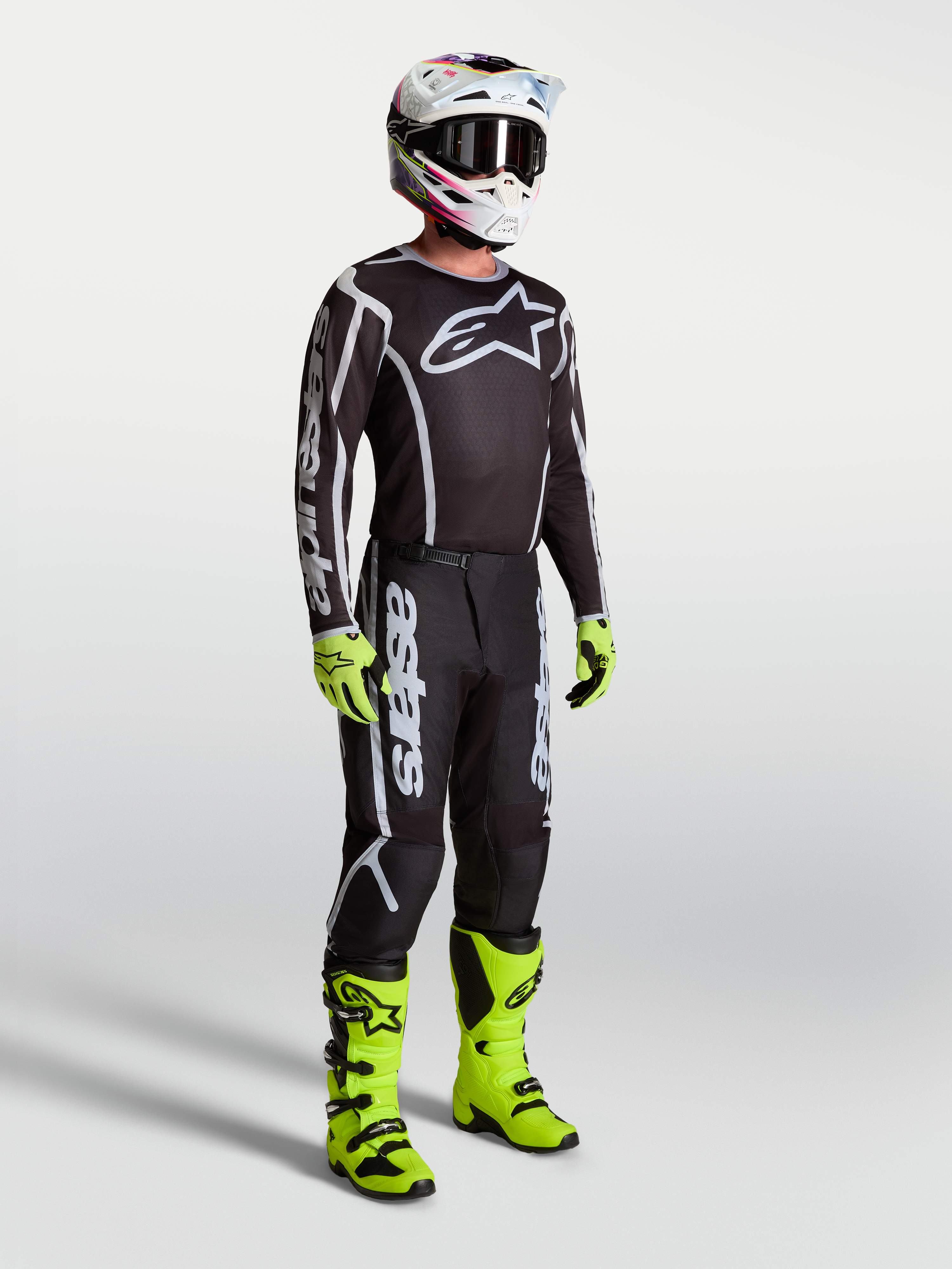 Alpinestars Fluid Apex V2 tröja, svart och silver motocrosströja på modell med neongröna stövlar och handskar.