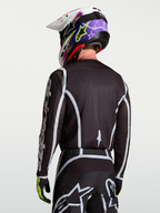Alpinestars Fluid Apex V2 tröja, motocrosströja i svart och silver, modell sedd bakifrån, fukttransporterande polytyg och ergonomisk skärning för racing.