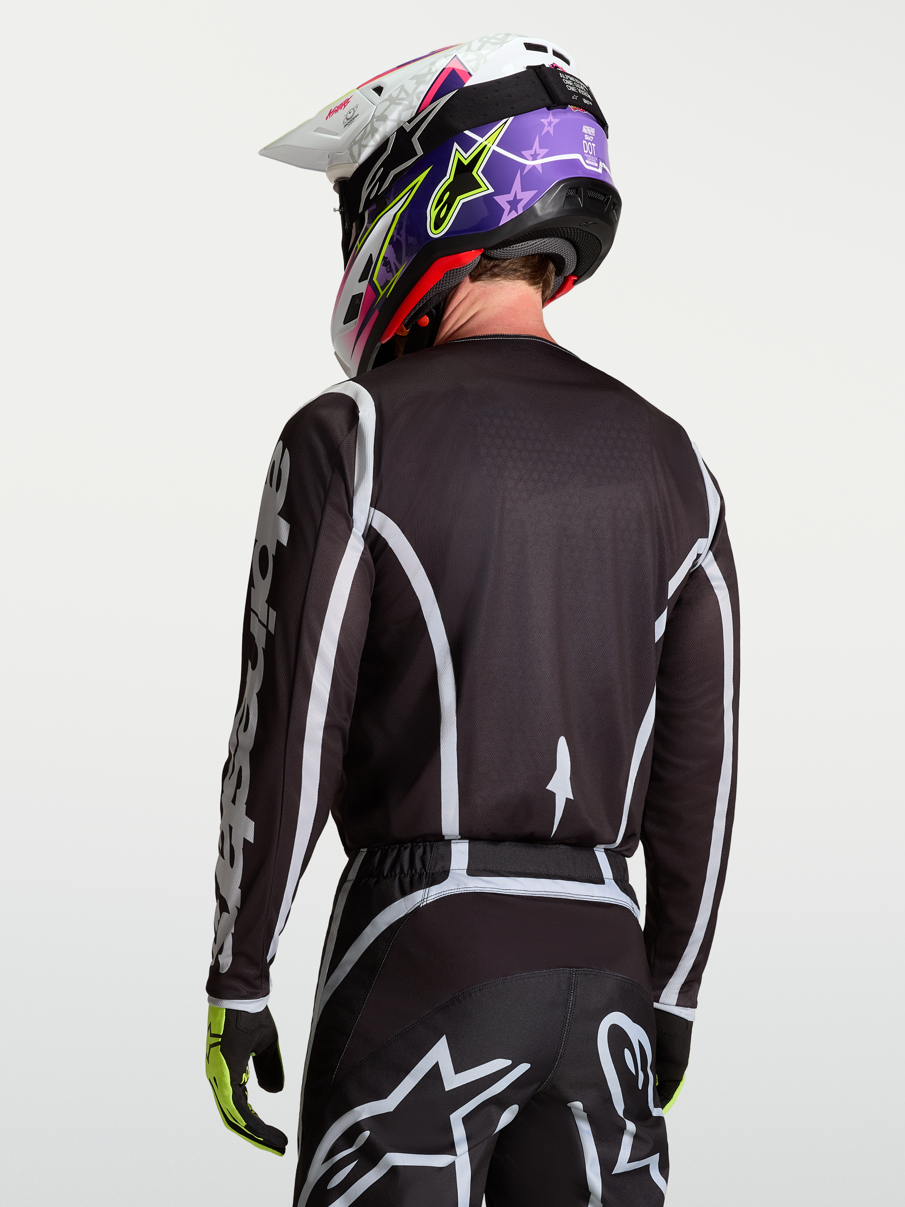 Alpinestars Fluid Apex V2 tröja, motocrosströja i svart och silver, modell sedd bakifrån, fukttransporterande polytyg och ergonomisk skärning för racing.