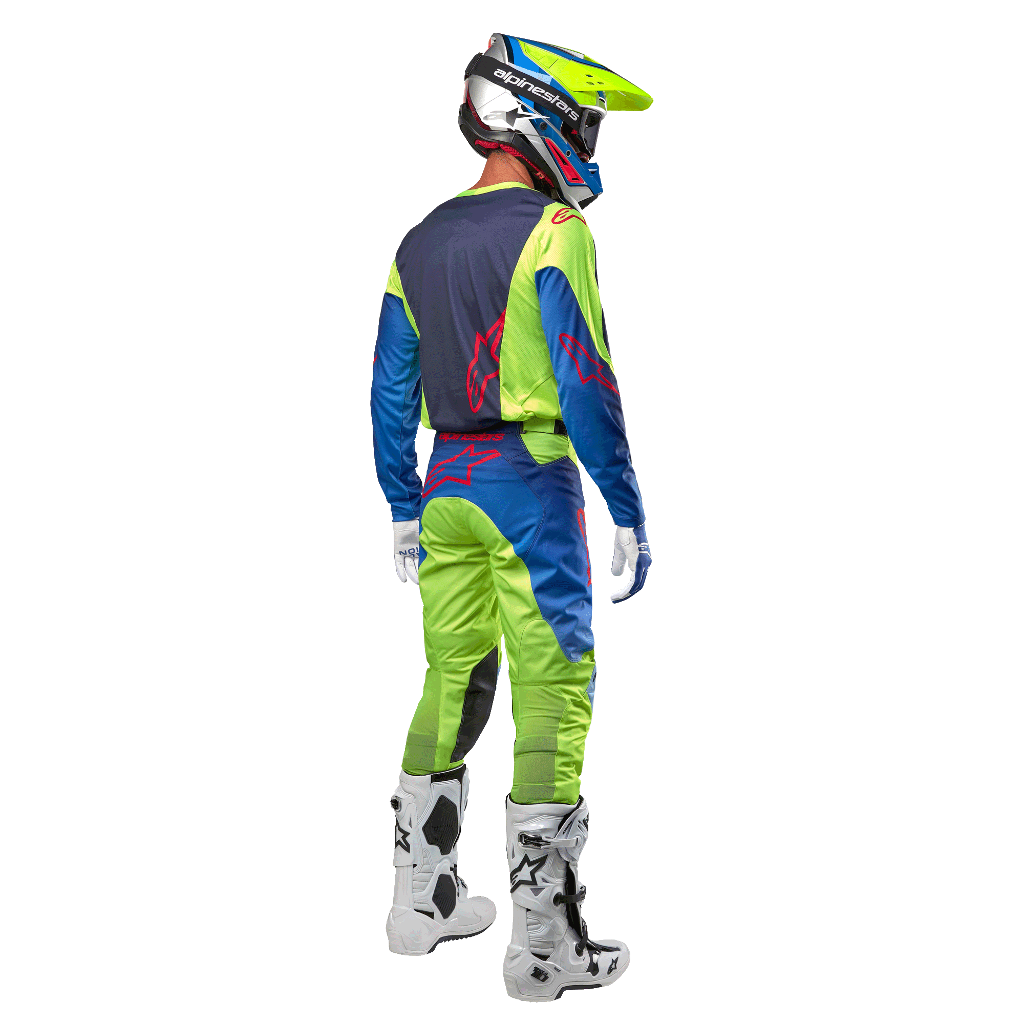 Motocrossförare sedd bakifrån i Alpinestars 2024 Racer Hoen-tröja i Yellow Fluo och Blue Night Navy, matchande motocrossbyxor och vita stövlar, visar ryggdesignen med röda logotyper, koordinerad outfit för professionell terrängkörning