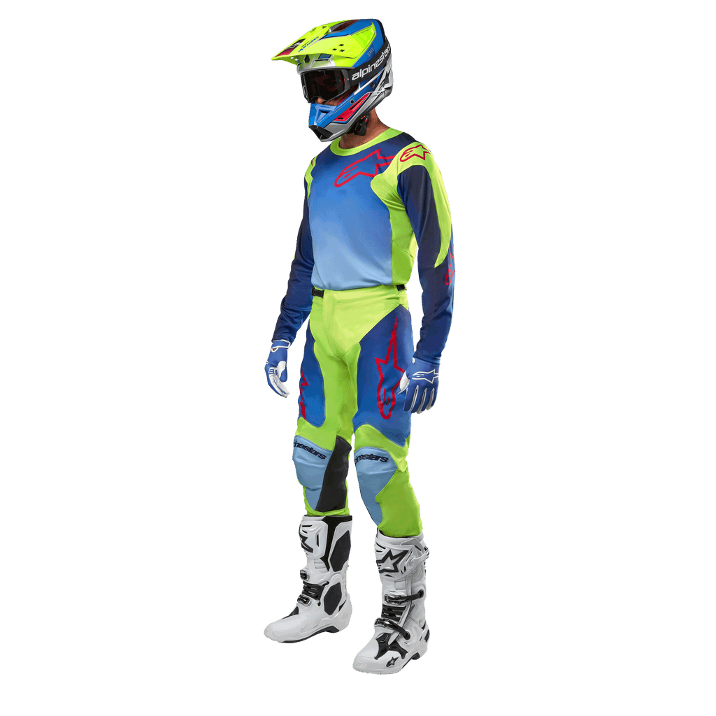 Alpinestars 2024 Racer Hoen tröja, motocrosströja, neongul och mörkblå, bärs av en förare med matchande byxor, hjälm och vita stövlar, professionell racingutrustning för terrängkörning