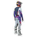 Motocrossförare sedd bakifrån bärande Alpinestars 2024 Racer Hoen Jersey i Light Gray Hot Orange Black, mörkblå ryggpanel med orange stjärnlogotyp, lila ärmar, bärs tillsammans med matchande racingbyxor och vita stövlar.
