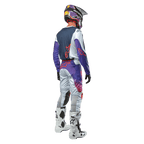 Alpinestars 2024 Racer Hoen byxor, ljusgrå motocrossbyxor med detaljer i varm orange och svart, komplett outfit för terrängkörning sedd bakifrån med matchande tröja, lila hjälm och vita stövlar, ergonomisk design för off-road-körning.