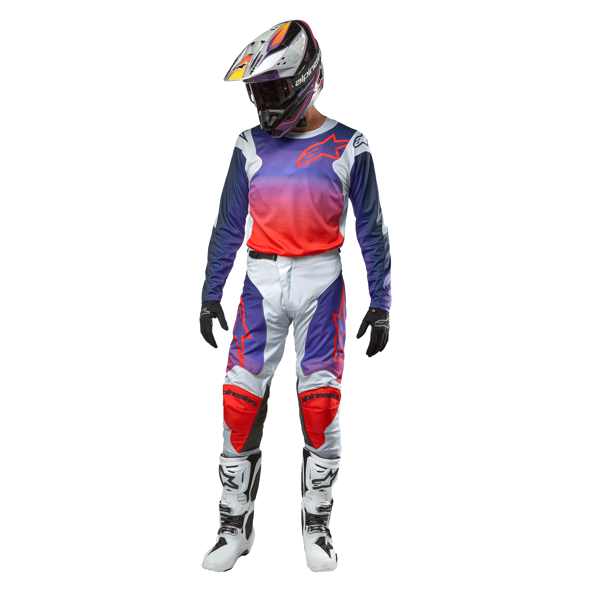 Motocrossförare iklädd komplett racingutrustning, Alpinestars 2024 Racer Hoen-tröja med lila till starkt orange toning och ljusgrå axlar, matchande ljusgrå byxor med röda och lila detaljer, koordinerad hjälm och vita stövlar, komplett outfit för terrängkörning