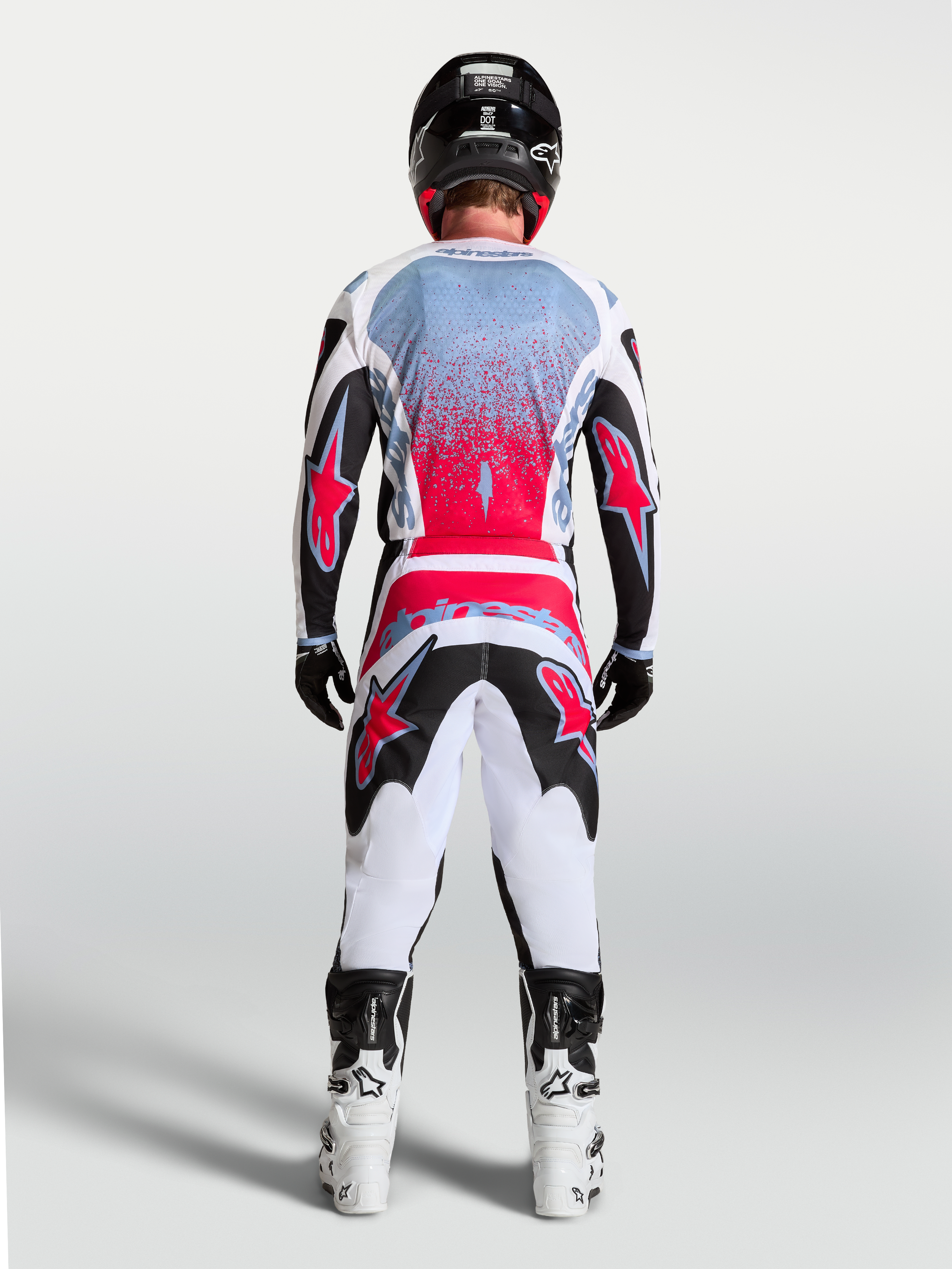 Alpinestars Fluid Drag tröja, motocrosströja för herr, svart och röd fluo med vita detaljer, vy bakifrån på en förare, ergonomisk design för optimal rörlighet vid terrängkörning.
