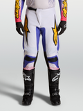 Alpinestars 2027 Fluid Drag byxor, ljuslila och blå motocrossbyxor för herr med gulddetaljer, visas på förare.