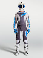 Alpinestars 2027 Fluid Drag utrustningsset, grå och blå motocrossoutfit med matchande tröja, byxor, vit hjälm och stövlar.