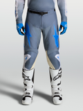 Alpinestars 2027 Racer Amber byxor, motocrossbyxor för herr, askgråa och blåa, visas på modell med vita motorcykelstövlar.