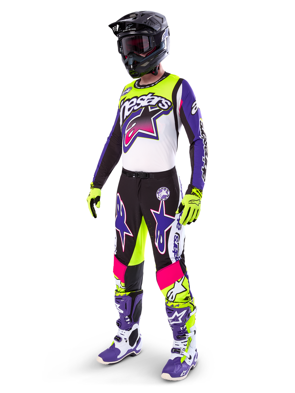 Motocrossförare i Alpinestars Limited Edition Supertech Dirt Studios®-utrustning, färgkombination i vitt, lila och neongult, svarta byxor med lila och rosa stjärnlogotyper, neongula handskar, lila och vita racingstövlar, svart hjälm, komplett professionell racingutrustning för terrängkörning