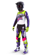 Motocrossförare i Alpinestars Limited Edition Supertech Dirt Studios®-utrustning, färgkombination i vitt, lila och neongult, svarta byxor med lila och rosa stjärnlogotyper, neongula handskar, lila och vita racingstövlar, svart hjälm, komplett professionell racingutrustning för terrängkörning