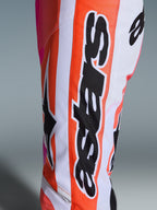 Alpinestars 2026 Racer Air Portl byxor, motocrossbyxor, orange, vita och rosa, närbild som visar stor svart Alpinestars-logotyp och stjärnsymbol, perforerat tyg för ventilation, hållbar racingutrustning för terrängkörning