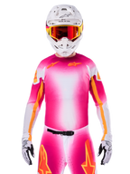 Alpinestars Limited Edition Supertech AFD MIG-tröja, rosa och vit motocrosströja med en livfull färgtoning och orangea stjärnlogotyper, bärs som ett komplett racingställ med matchande byxor, vit hjälm och röda goggles, professionell utrustning för terrängkörning