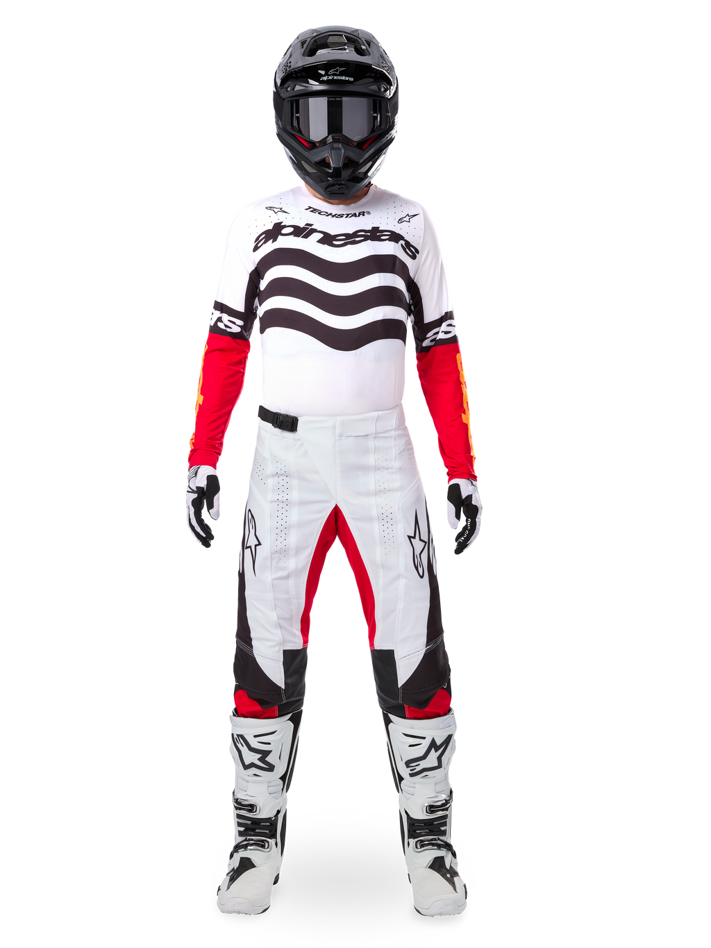 Motocross rider wearing the Alpinestars Limited Edition Techstar Deep Gear Set, white jersey with black wave graphics and red sleeves, matching white and black pants with red inner thigh accents, black helmet with dark goggles, and white boots, full professional off-road racing outfit