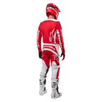 Vy bakifrån på en motocrossförare iklädd Alpinestars 2024 Fluid Lurv-tröja i Mars Red White, kombinerad med matchande röda och vita byxor, vita offroad-stövlar och en röd hjälm, som visar tröjans ryggdesign och Alpinestars logotyper.