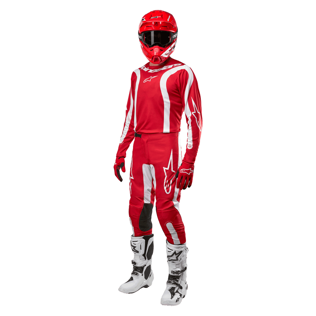 Motocrossförare i komplett racingutrustning, Alpinestars 2024 Fluid Lurv-tröja i Mars Red och vitt, matchande röda byxor med vita detaljer, röd hjälm, röda handskar och vita och svarta stövlar, koordinerad outfit för terrängkörning