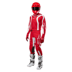Motocrossförare i komplett racingutrustning, Alpinestars 2024 Fluid Lurv-tröja i Mars Red och vitt, matchande röda byxor med vita detaljer, röd hjälm, röda handskar och vita och svarta stövlar, koordinerad outfit för terrängkörning