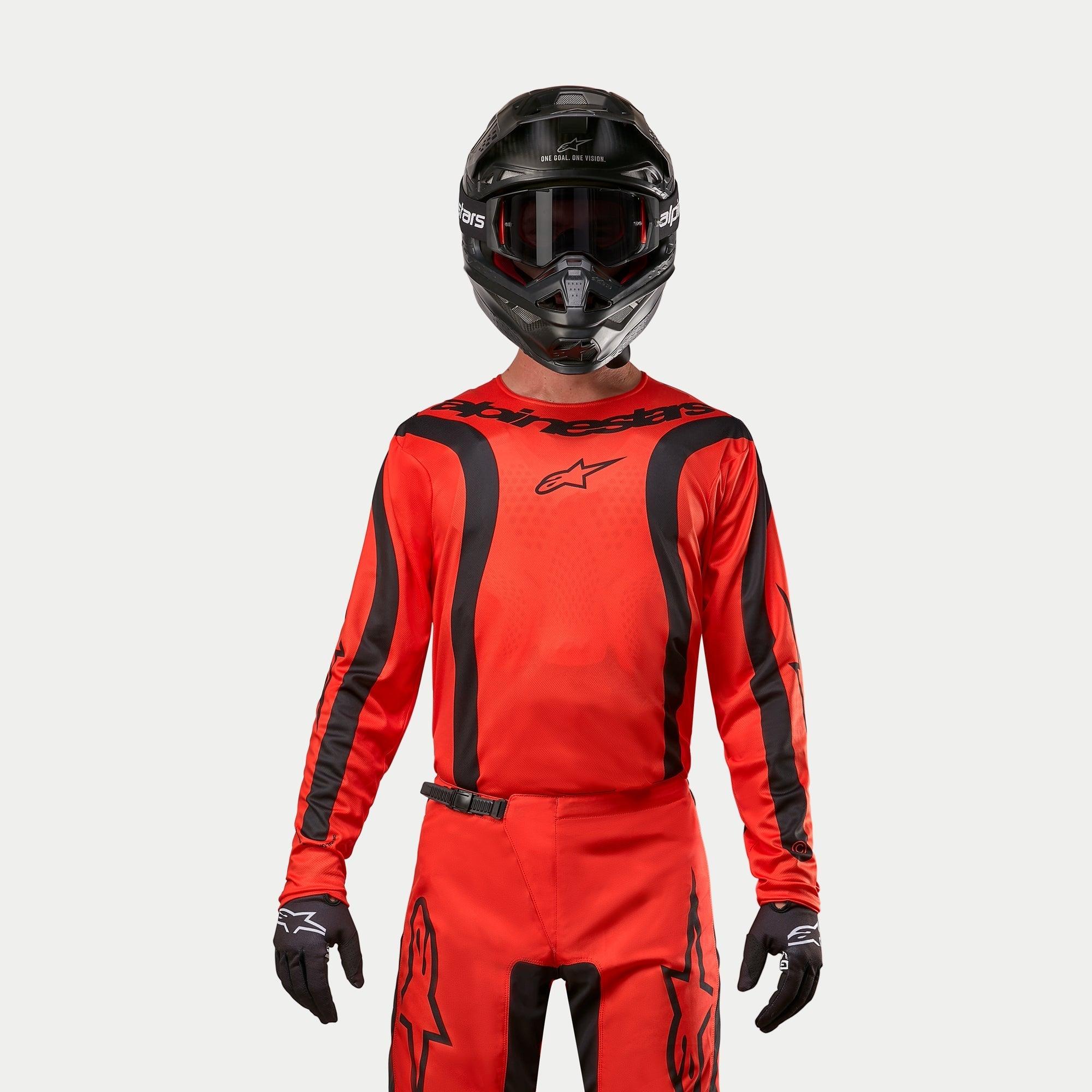 Motocrossförare iklädd Alpinestars 2024 Fluid Lurv-tröja, Hot Orange och svart, matchande motocrossbyxor, svart hjälm med goggles och svarta handskar, koordinerad utrustning för terrängkörning