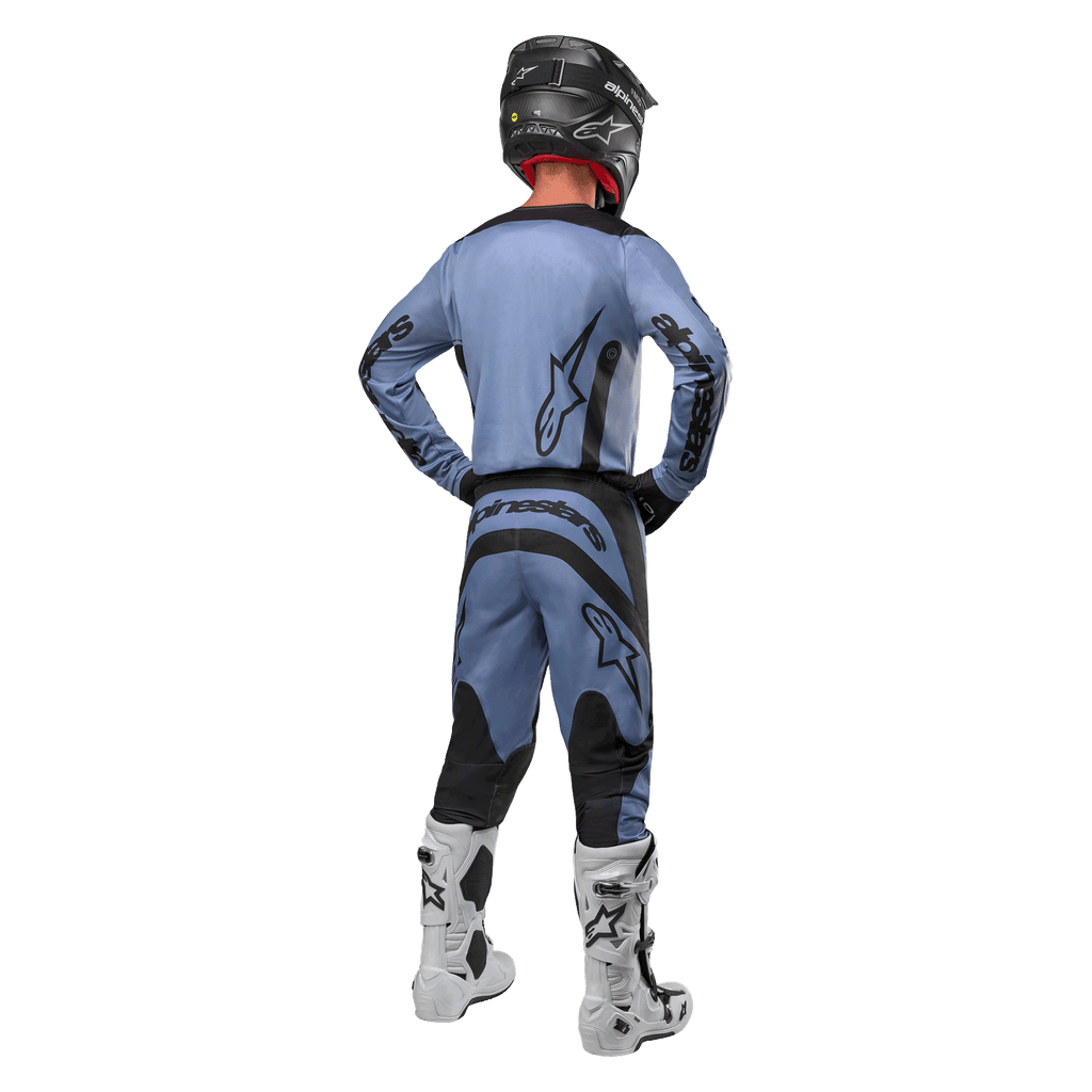 Motocross rider from behind wearing the Alpinestars 2024 Fluid Lurv Jersey and matching pants in Light Blue and Black, featuring black branding on the back and sleeves, paired with a black helmet and white boots.