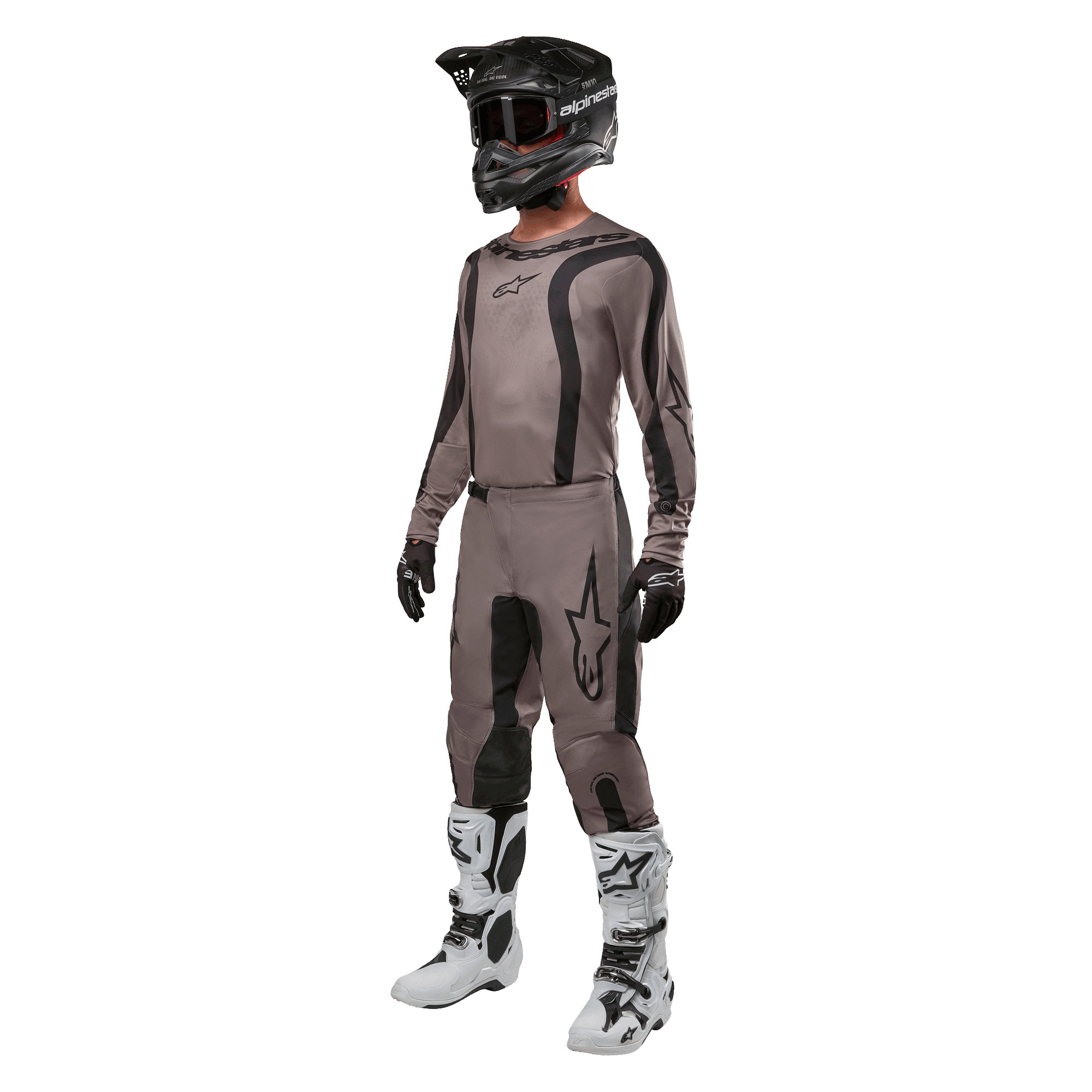 Motocrossförare i komplett racingutrustning med Alpinestars 2024 Fluid Lurv-tröja i Mud Black, matchande byxor, svart hjälm med goggles, vita och svarta stövlar och svarta handskar, koordinerad outfit för terrängkörning