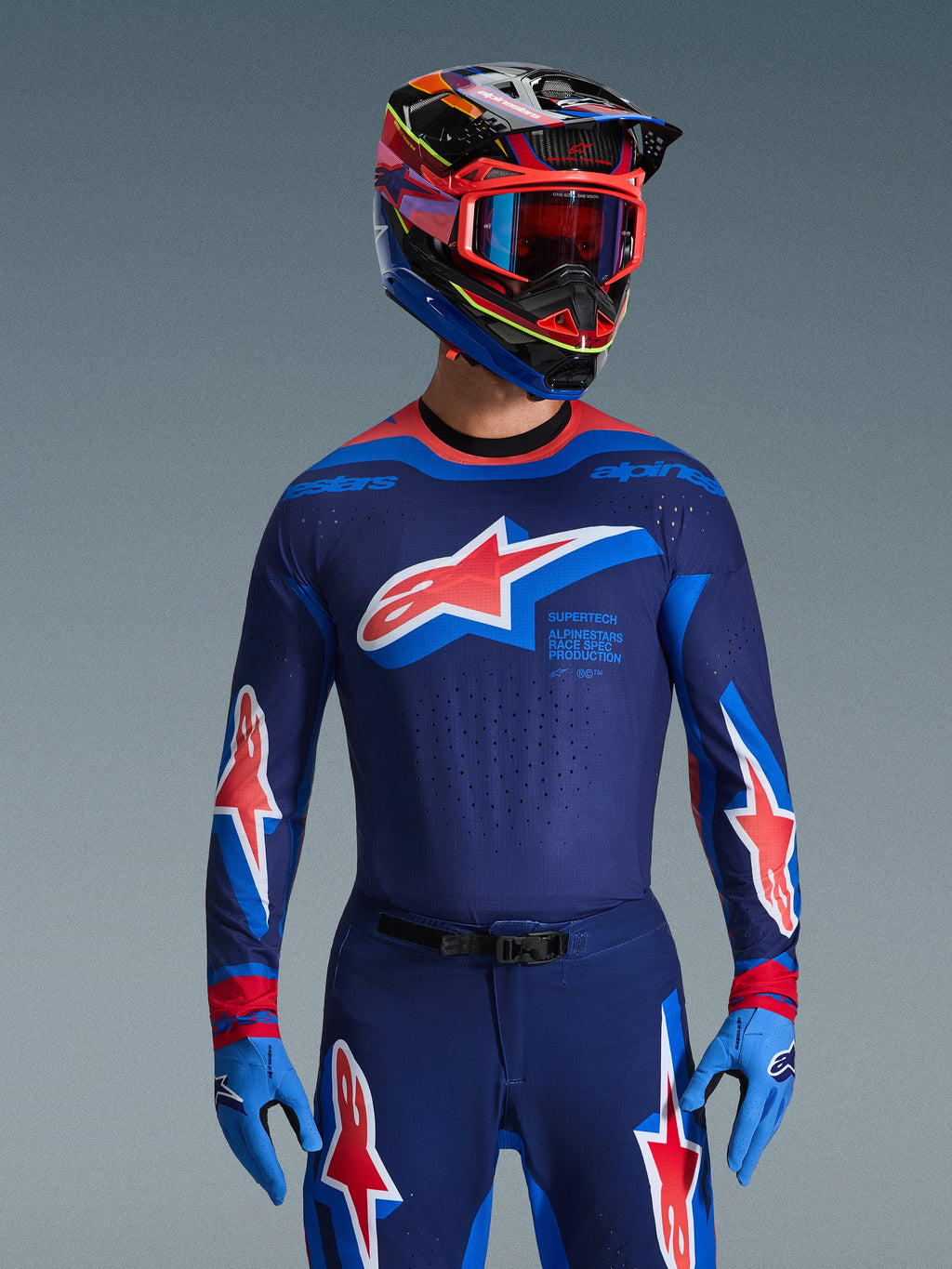 Alpinestars 2026 Supertech Vista utrustningsset, professionella motocrosskläder, mörkblå tröja och byxor med framträdande röda och vita stjärnlogotyper, kombinerat med en flerfärgad racinghjälm, röda goggles och ljusblå handskar, koordinerad racingoutfit på proffsnivå
