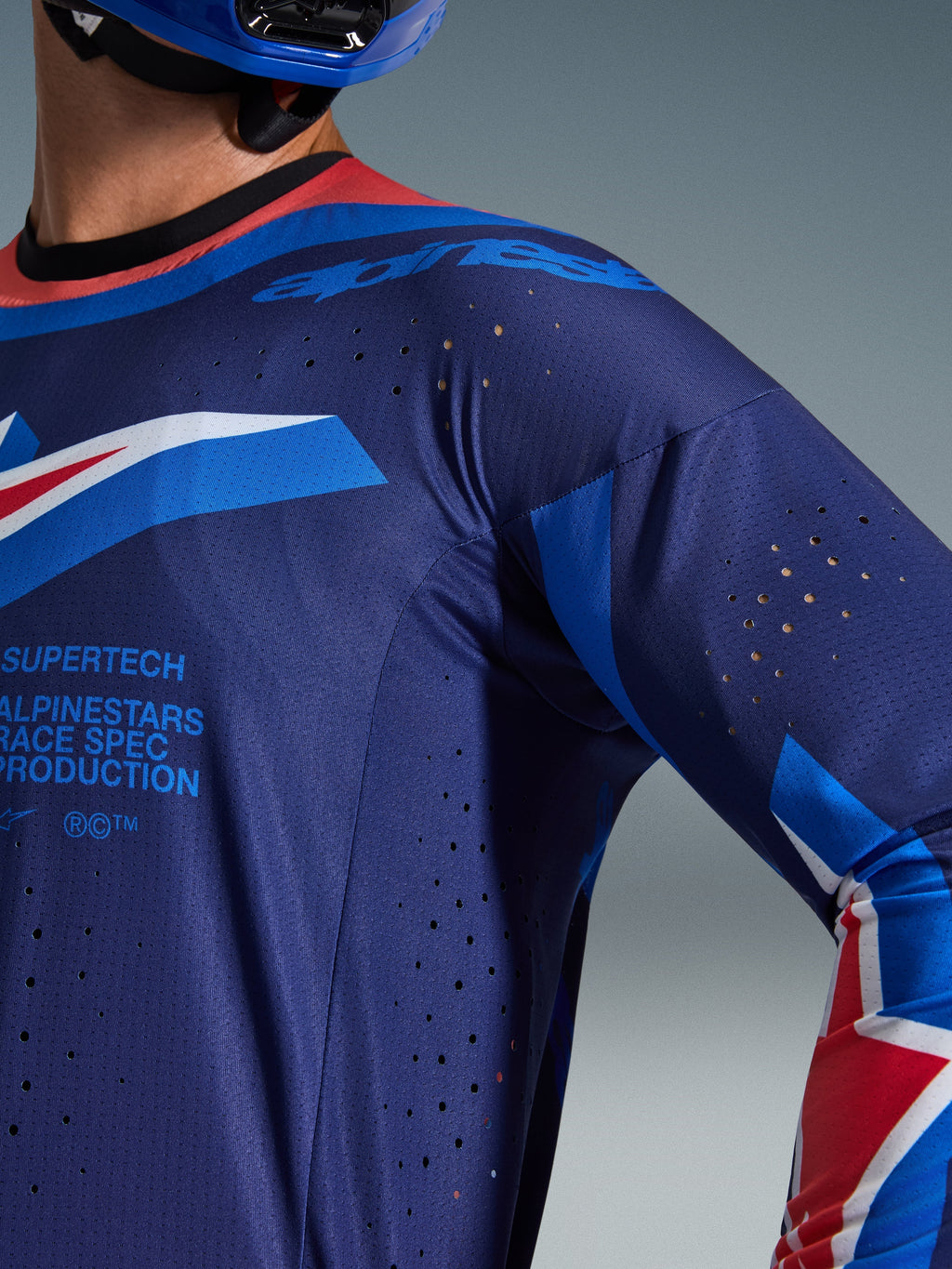 Alpinestars 2026 Supertech Vista-tröja, närbild på mörkblå och koboltblå jersey med Hot Coral-krage, laserskurna ventilationsperforeringar och Alpinestars Race Spec-branding, atletisk premiumkonstruktion i mesh för motocrossracing.