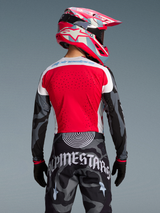 Alpinestars Techstar Beast Coast utrustningsset, röd tröja, kamouflagebyxor och färgstark rosa hjälm, sett bakifrån.