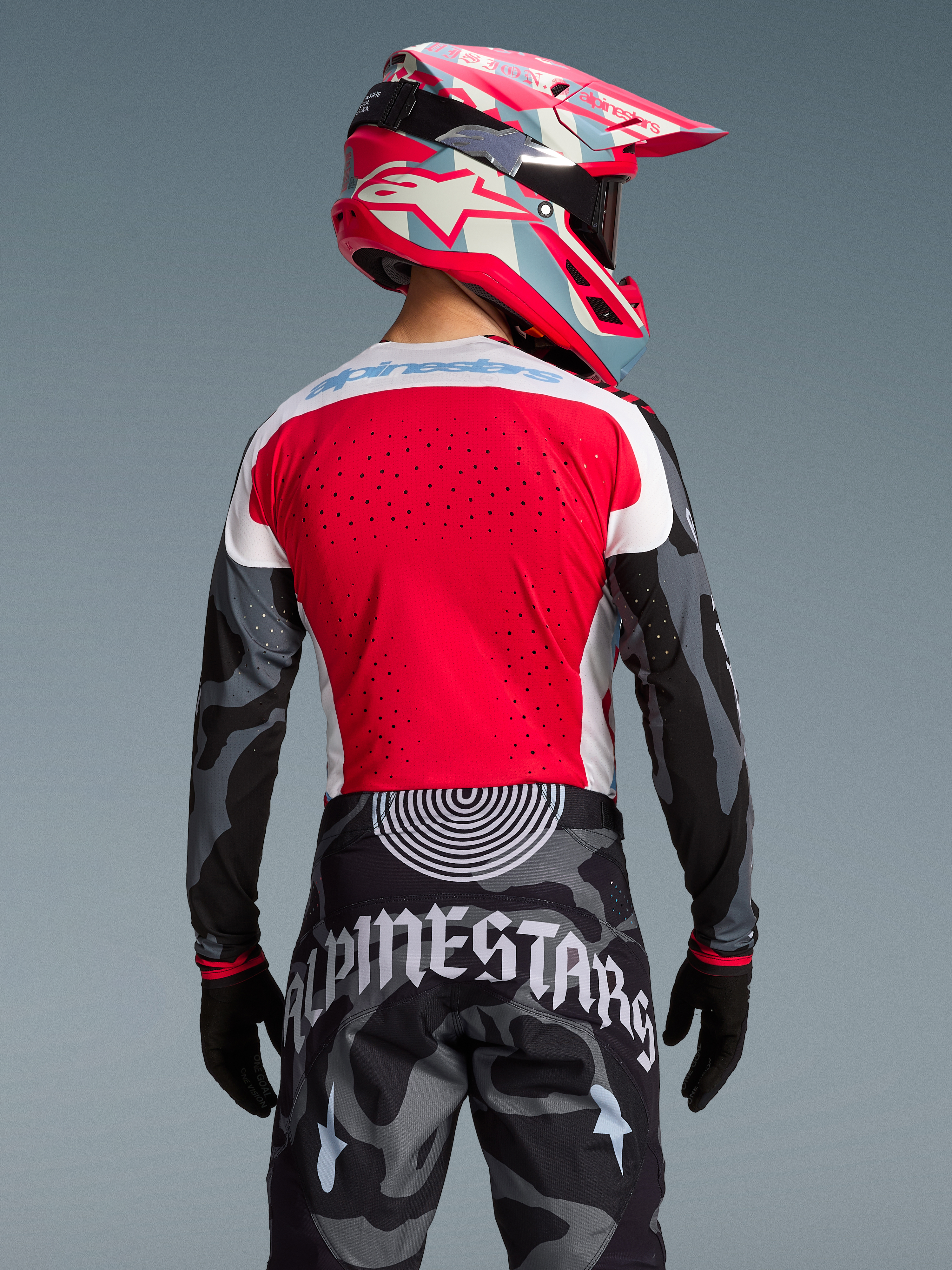 Alpinestars Techstar Beast Coast utrustningsset, röd tröja, kamouflagebyxor och färgstark rosa hjälm, sett bakifrån.