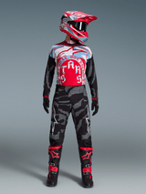 Alpinestars Techstar Beast Coast-ställ, röd/blå tröja, grå kamouflagebyxor, matchande hjälm och svarta racingstövlar.
