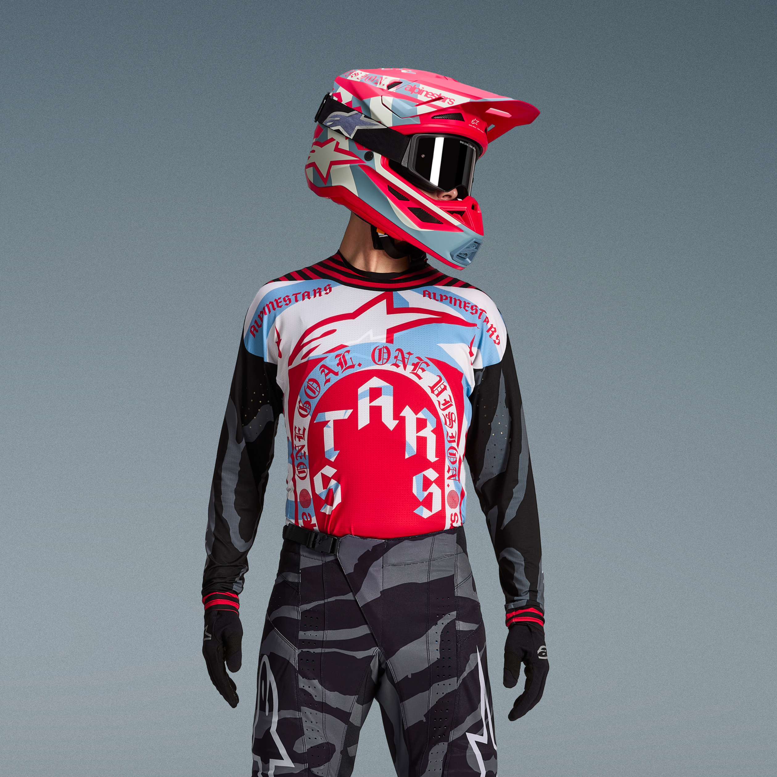 Alpinestars Techstar Beast Coast-set, röd och blå tröja, grå kamouflagebyxor och matchande rosa hjälm med svarta goggles.