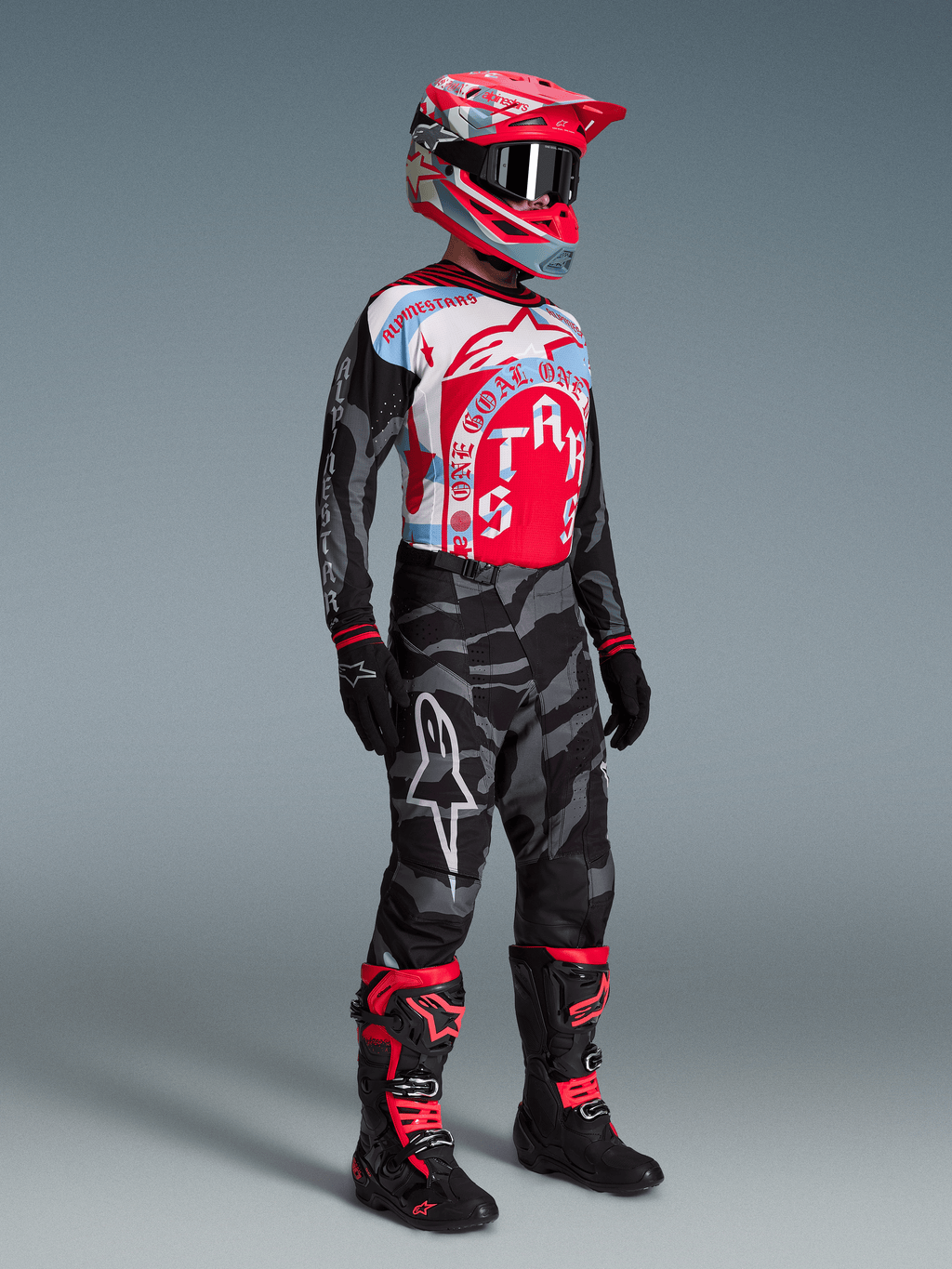 Alpinestars Techstar Beast Coast utrustningsset, förare i röd och blå tröja, kamouflagebyxor och matchande röd hjälm.
