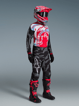Alpinestars Techstar Beast Coast utrustningsset, förare i röd och blå tröja, kamouflagebyxor och matchande röd hjälm.