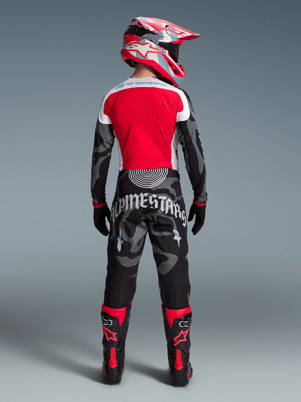 Alpinestars Techstar Beast Coast-set, motocrossförare bakifrån i röd tröja, kamouflagemönstrade byxor och matchande hjälm.