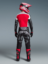 Alpinestars Techstar Beast Coast-set, motocrossförare bakifrån i röd tröja, kamouflagemönstrade byxor och matchande hjälm.