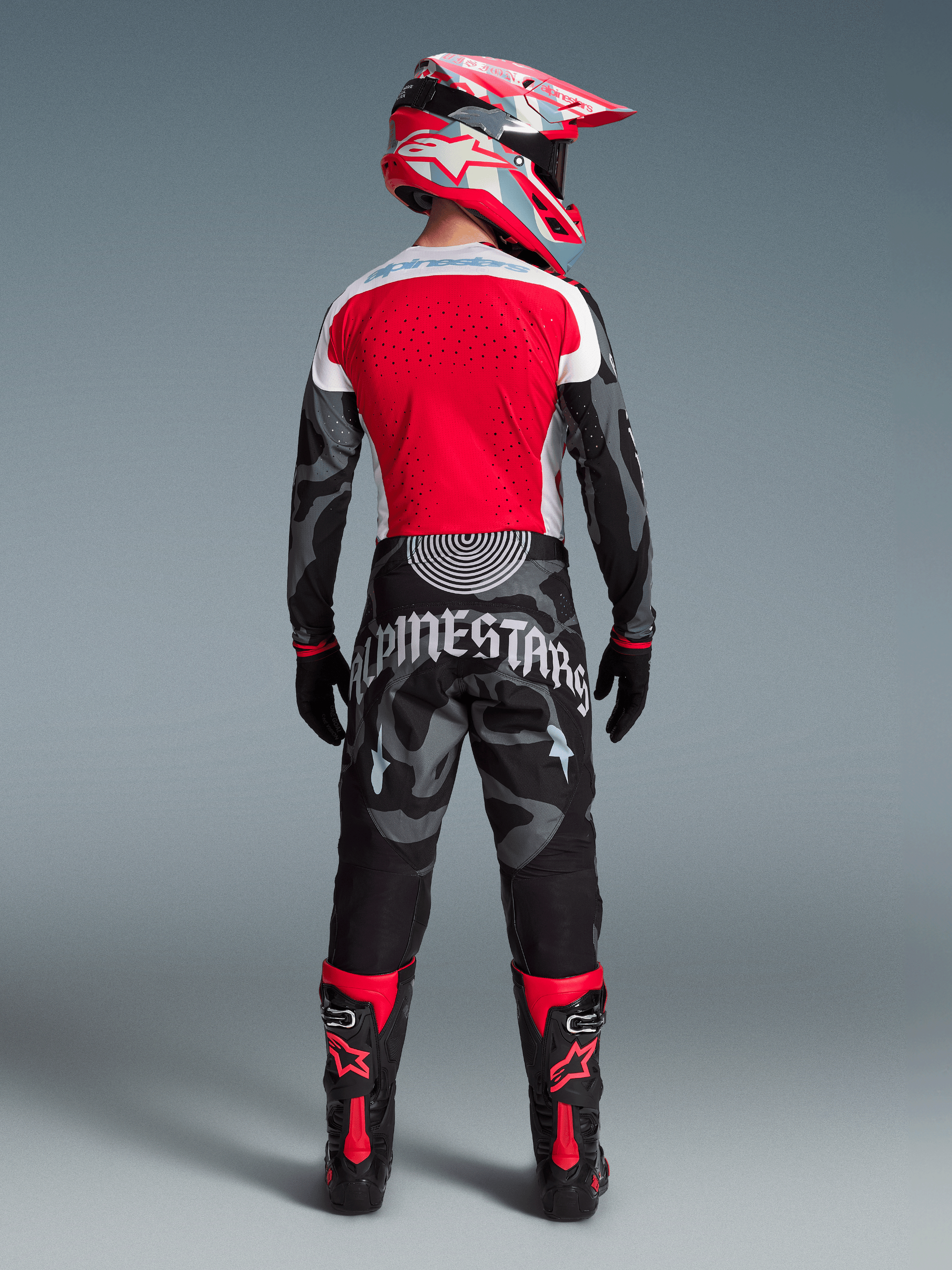 Alpinestars Techstar Beast Coast-set, motocrossförare bakifrån i röd tröja, kamouflagemönstrade byxor och matchande hjälm.