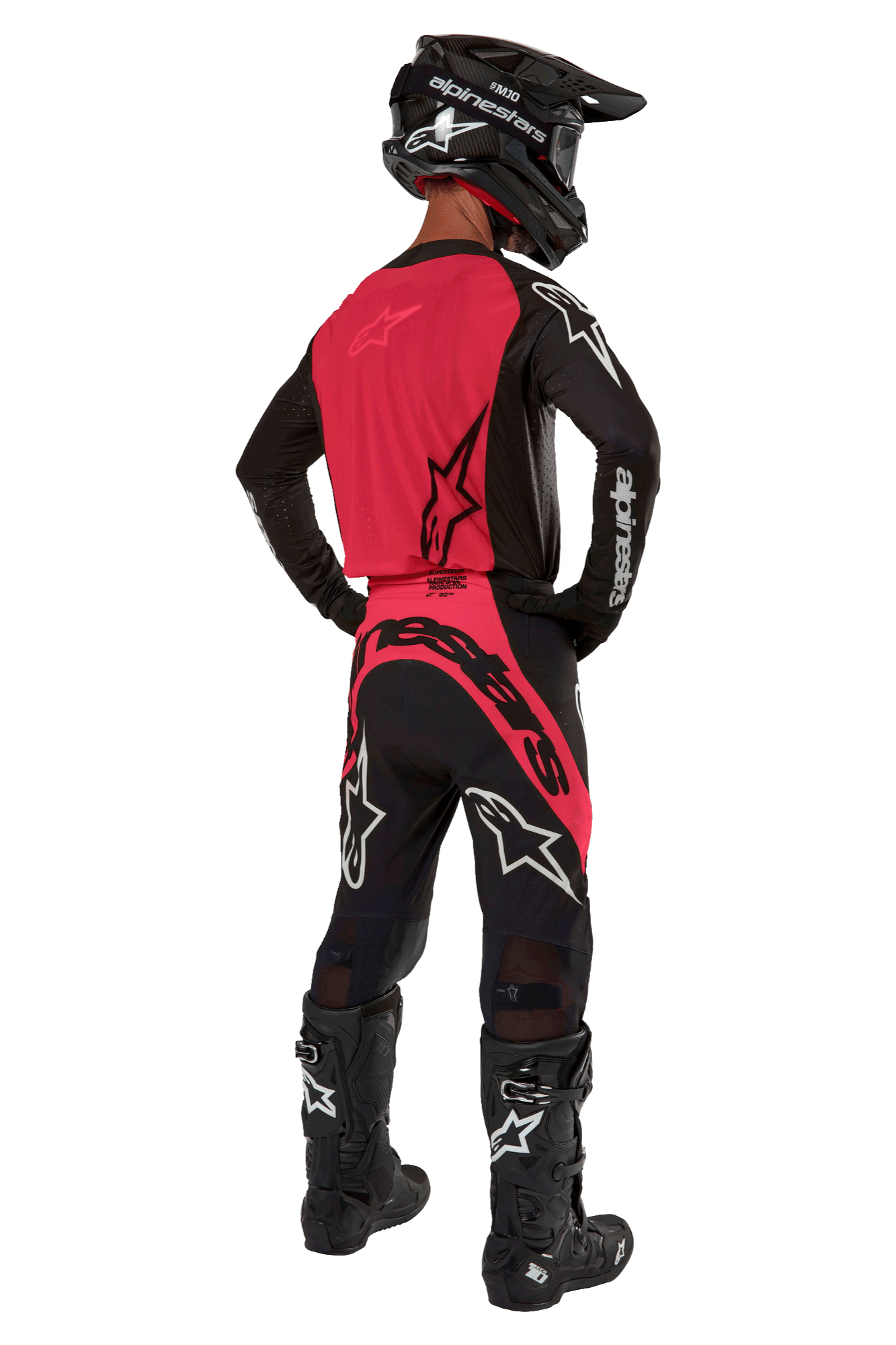 Motocross rider from behind wearing the 2024 Supertech Ward Jersey in Black Red Berry, featuring a vibrant red back panel and black sleeves with white Alpinestars branding. Paired with matching motocross pants, black Tech 10 boots, and a black carbon fiber helmet for a coordinated professional racing gear set.