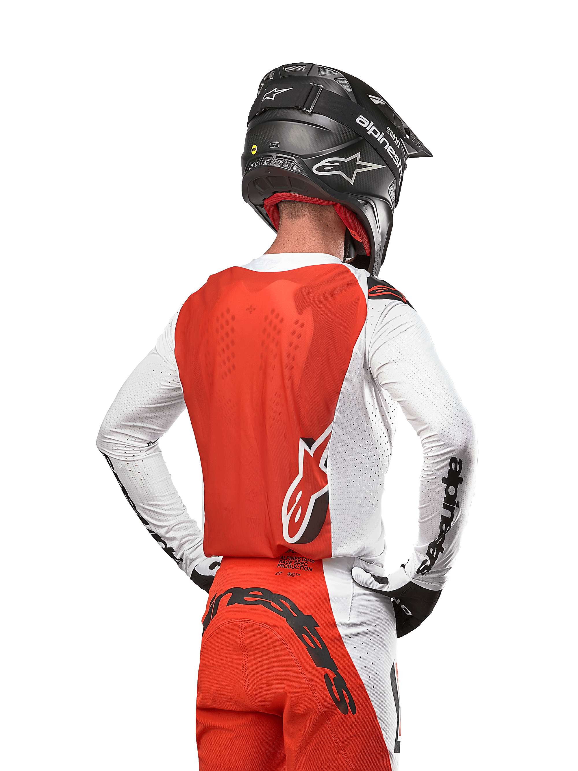 Motocrossförare i 2024 Supertech Ward Jersey i White Hot Orange, sedd bakifrån med orange ryggpanel och vita ärmar med svart Alpinestars-branding, matchad med matchande byxor och en svart hjälm, professionell utrustning för terrängkörning