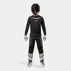 Motocross rider wearing complete racing gear, Alpinestars 2024 Fluid Graphite Jersey in Black Silver, black pants with silver star logos, black helmet with red goggles, white and black boots, white and black gloves, coordinated motocross outfit
