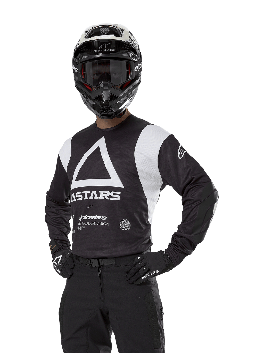 Alpinestars Techdura Jersey, motocrosströja, svart och vit, bärs med matchande hjälm och handskar, pose med händerna på höfterna mot vit bakgrund, med stor triangelformad A-logotyp och ASTARS-branding