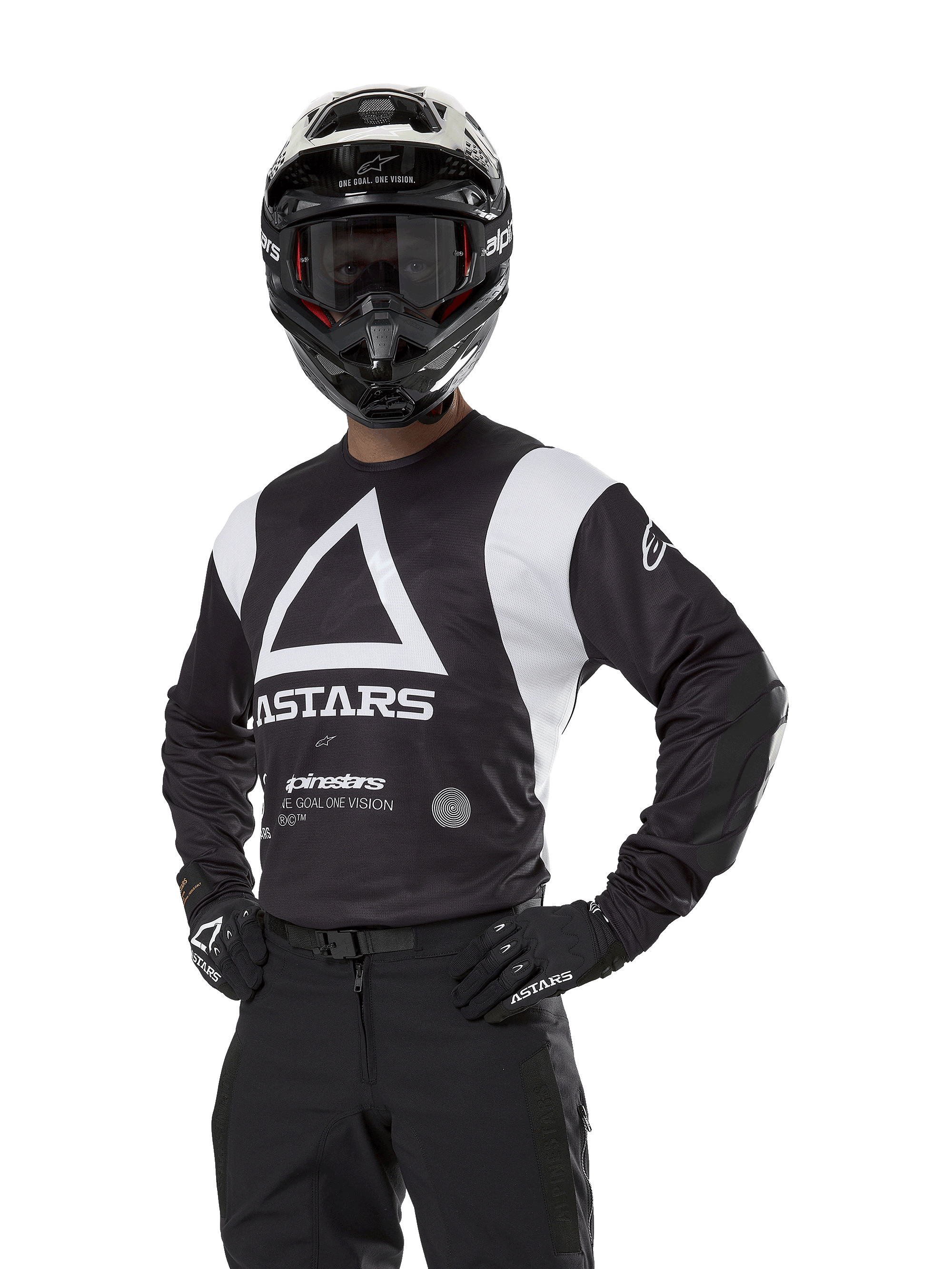 Alpinestars Techdura Jersey, motocrosströja, svart och vit, bärs med matchande hjälm och handskar, pose med händerna på höfterna mot vit bakgrund, med stor triangelformad A-logotyp och ASTARS-branding