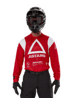Motocrossförare som bär Alpinestars Techdura-tröja, klarröd med vit grafik, med en stor vit triangel och ASTARS-logotyp på bröstet, kombinerad med en svart hjälm, svarta goggles och svart körutrustning, koordinerad outfit för enduro och offroad-racing
