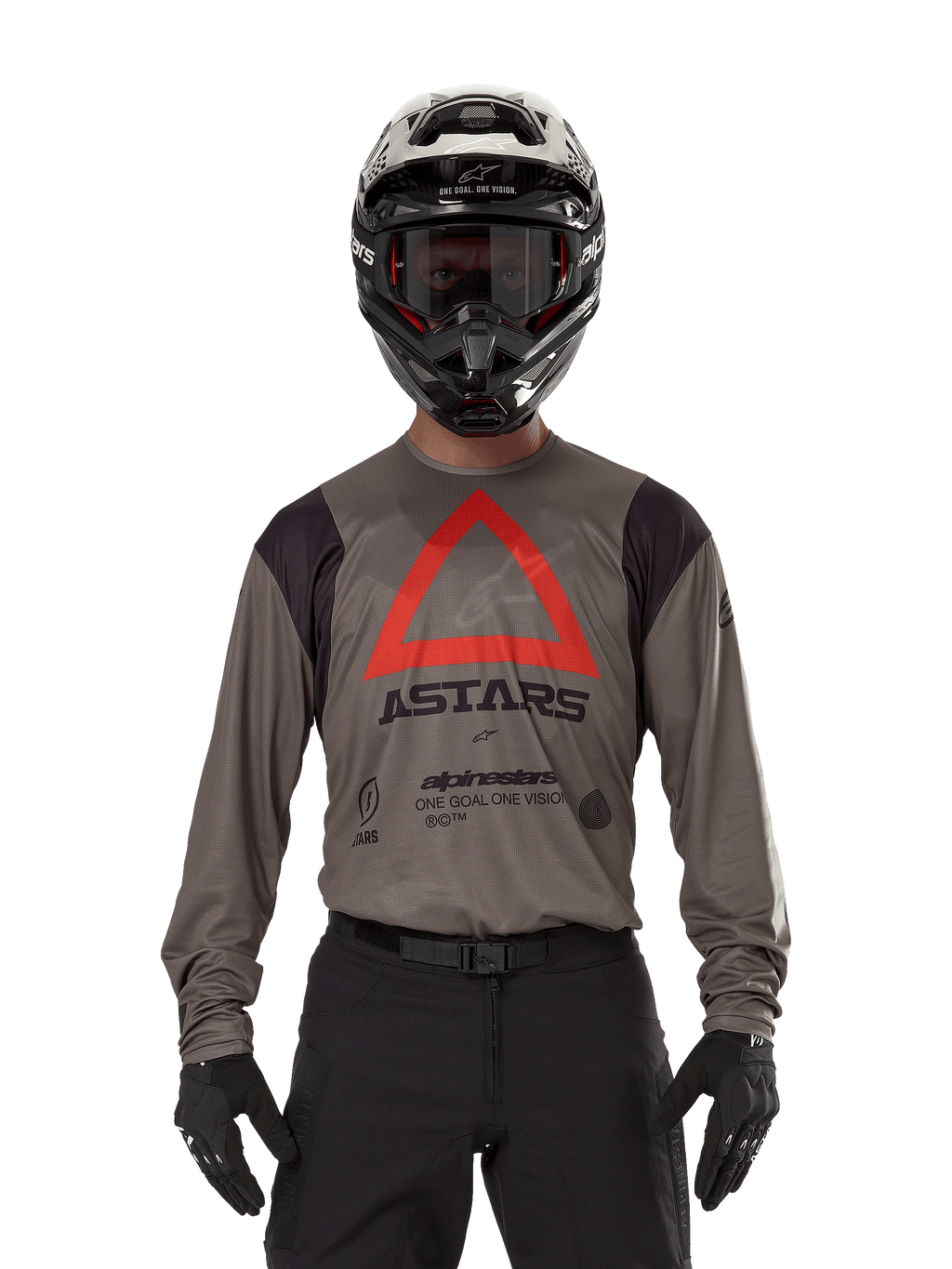 Motocross rider wearing Alpinestars Techdura Jersey in Falcon Brown, featuring a prominent red triangle and 'ASTARS' branding on the chest, paired with black pants, a black helmet with goggles, and black gloves, complete enduro racing outfit.