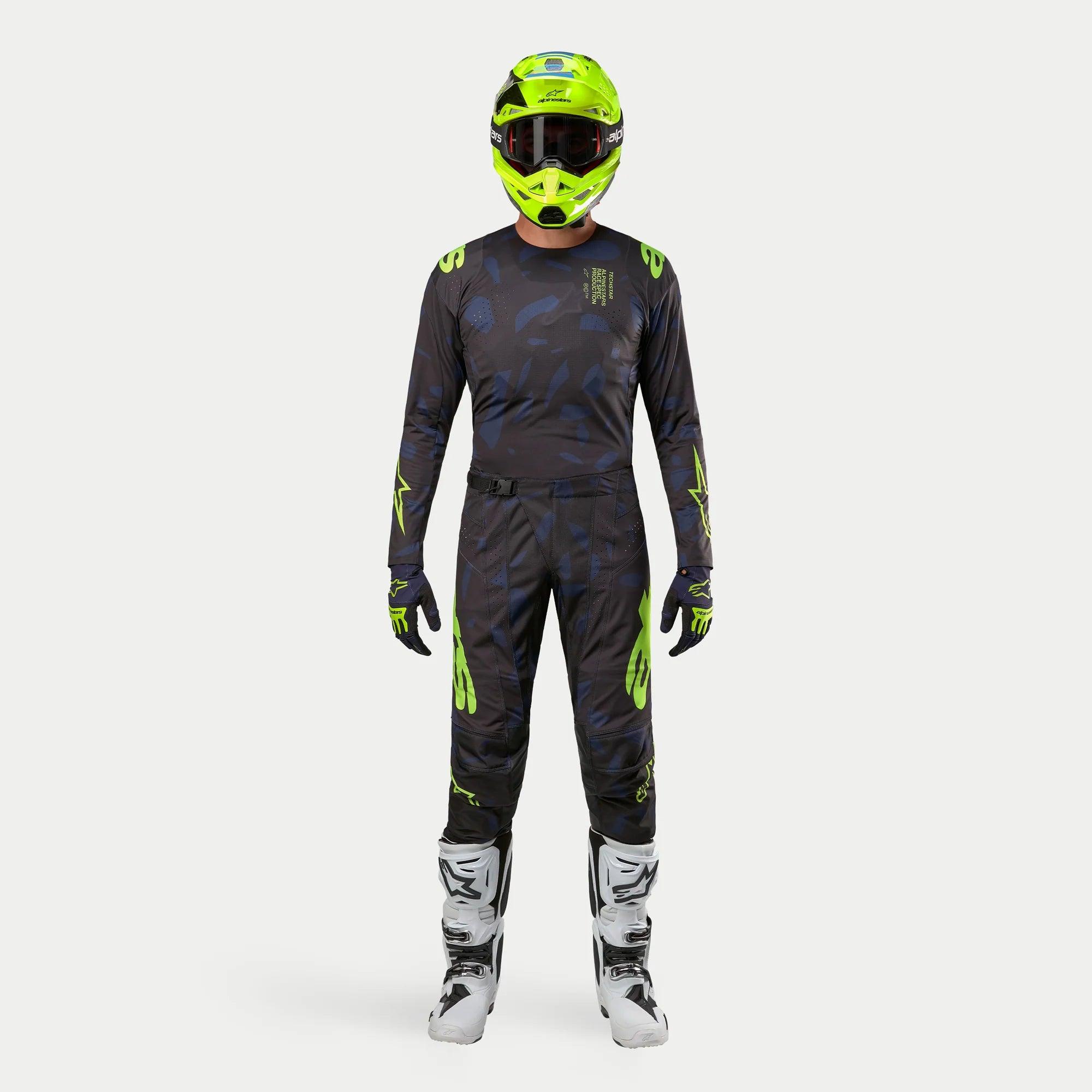 Motocrossförare i komplett racingutrustning, 2024 Techstar Rantera-tröja i Black Navy och Yellow Fluo, matchande byxor med abstrakt tryck, neongul hjälm, vita och svarta stövlar, koordinerad outfit för terrängkörning