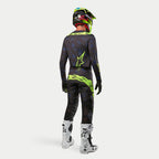 Alpinestars 2024 Techstar Rantera-tröja, motocrosströja, svart, marinblå och neongul, buren med matchande byxor, vita och svarta stövlar och en neongul hjälm, sedd bakifrån i komplett offroad-racingutrustning