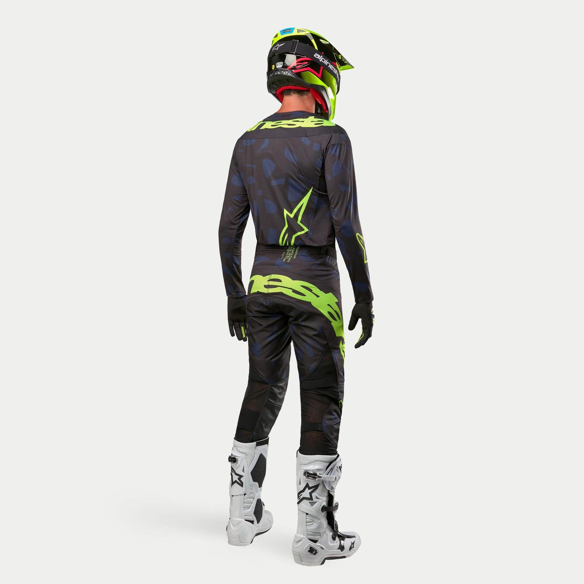 Alpinestars 2024 Techstar Rantera-tröja, motocrosströja, svart, marinblå och neongul, buren med matchande byxor, vita och svarta stövlar och en neongul hjälm, sedd bakifrån i komplett offroad-racingutrustning