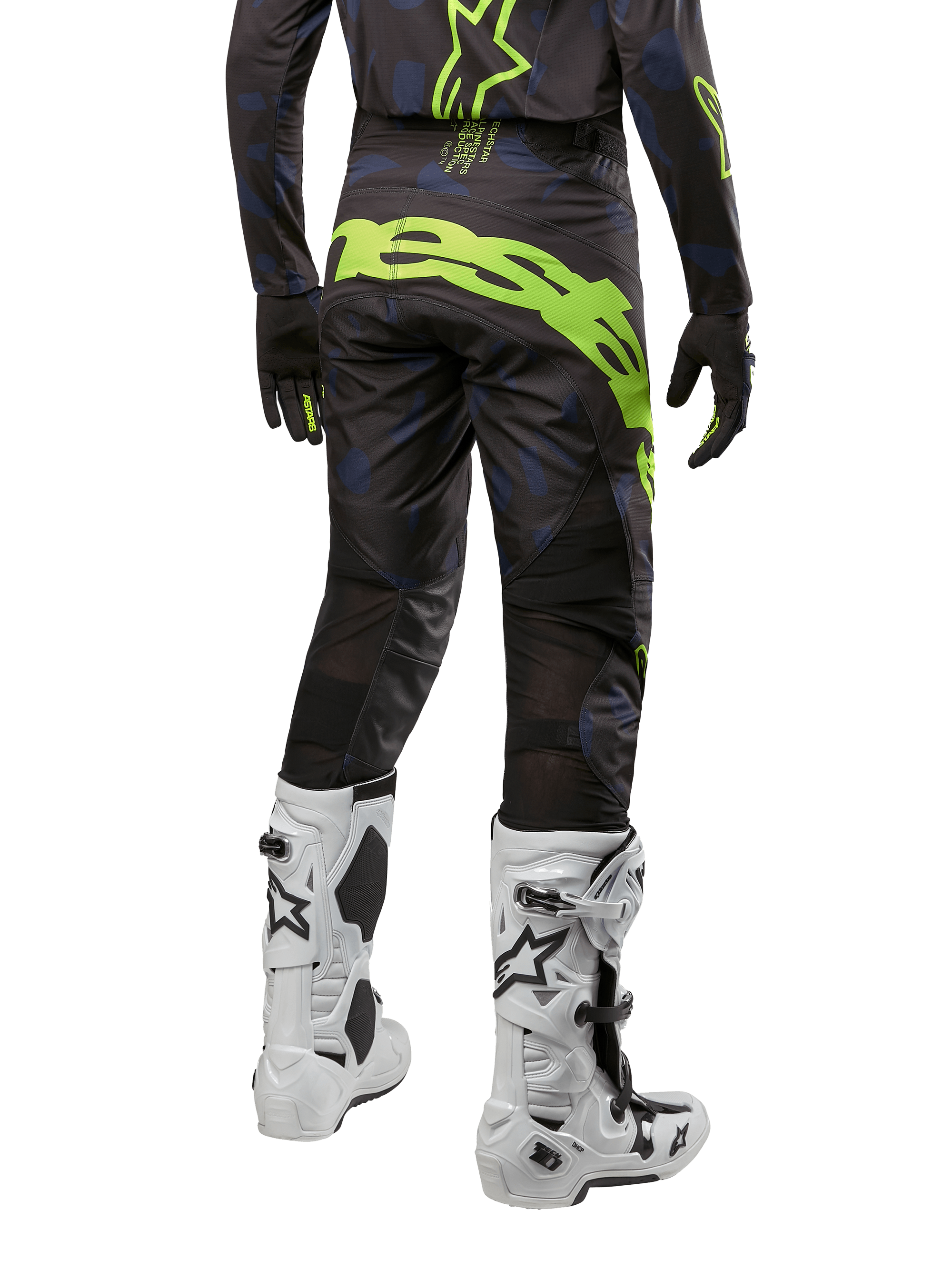 Alpinestars 2024 Techstar Rantera byxor, motocrossbyxor, svarta, marinblå och neongula, vy bakifrån, med framträdande neongul logotyp och ventilationspaneler i mesh, bärs med matchande tröja och vita stövlar, slitstark utrustning för motocross och terrängkörning