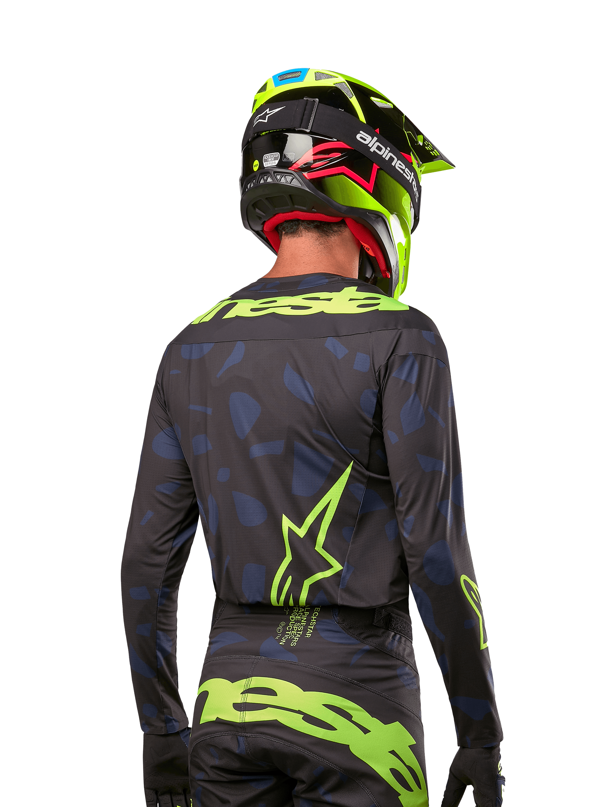 Vy bakifrån av en motocrossförare i Alpinestars 2024 Techstar Rantera Jersey i Black Navy Yellow Fluo, med framträdande neongul branding och logotyper på ryggen, matchad med matchande motocrossbyxor och en neongul hjälm för en komplett offroad-look.